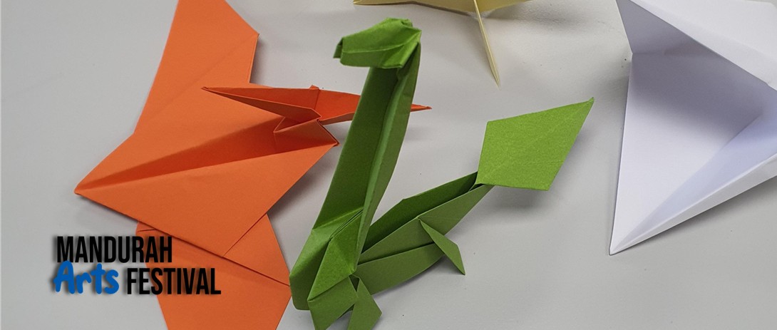 Origami creatures resembling underwater and flying dinosaurs, made from orange, green and white paper against a white background